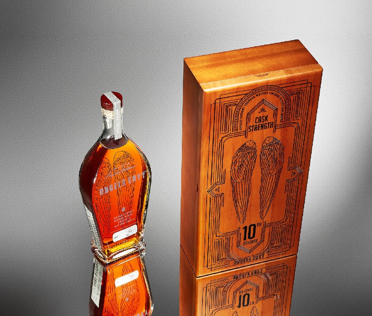 Bottle of whiskey next to box with wings etched on front