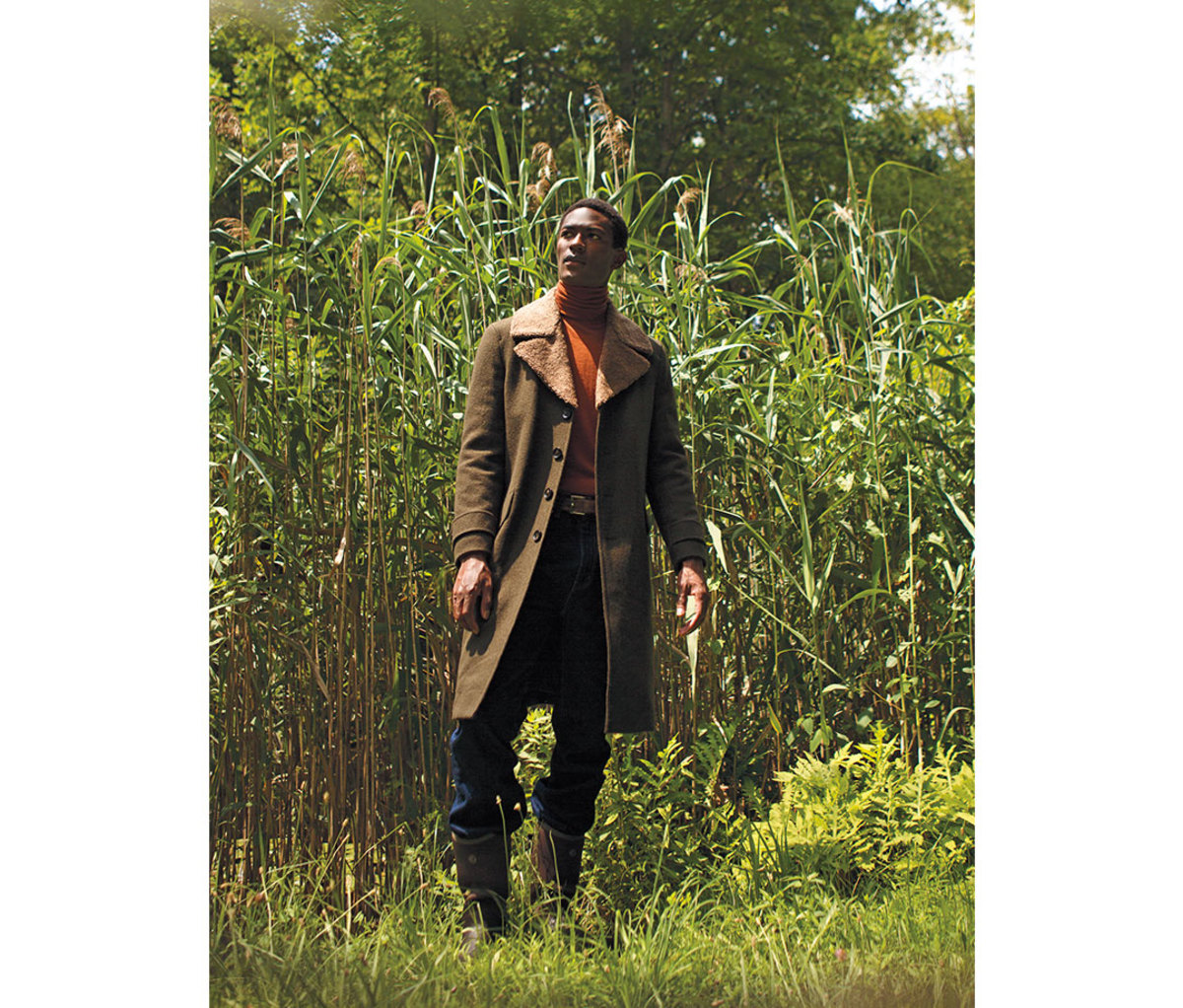Black male model wearing double-breasted coat in corn field