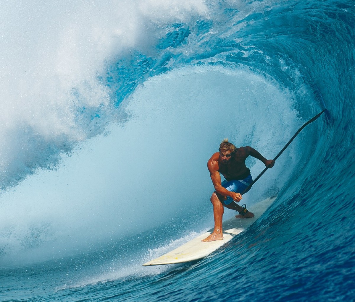 Laird Hamilton riding big wave on paddleboard with paddle