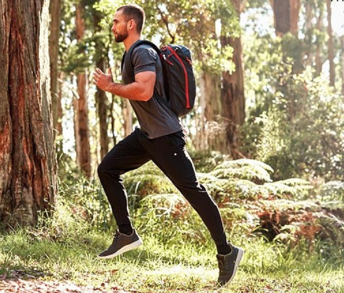 Man jogging in the woods in a pair of black Thousand Miles All Day Pants