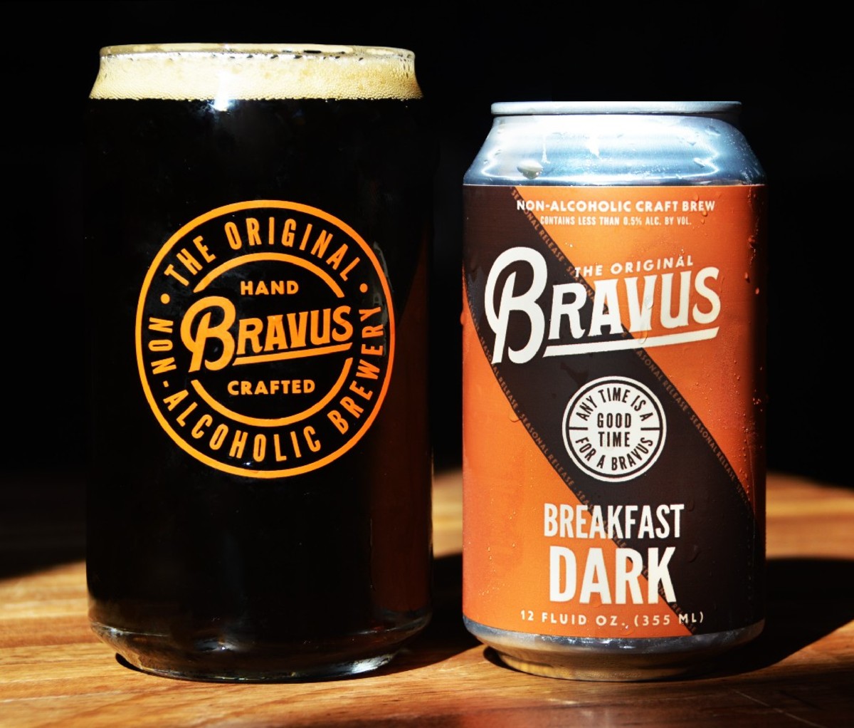 Can and full pint of Bravus Breakfast Dark on a wooden surface