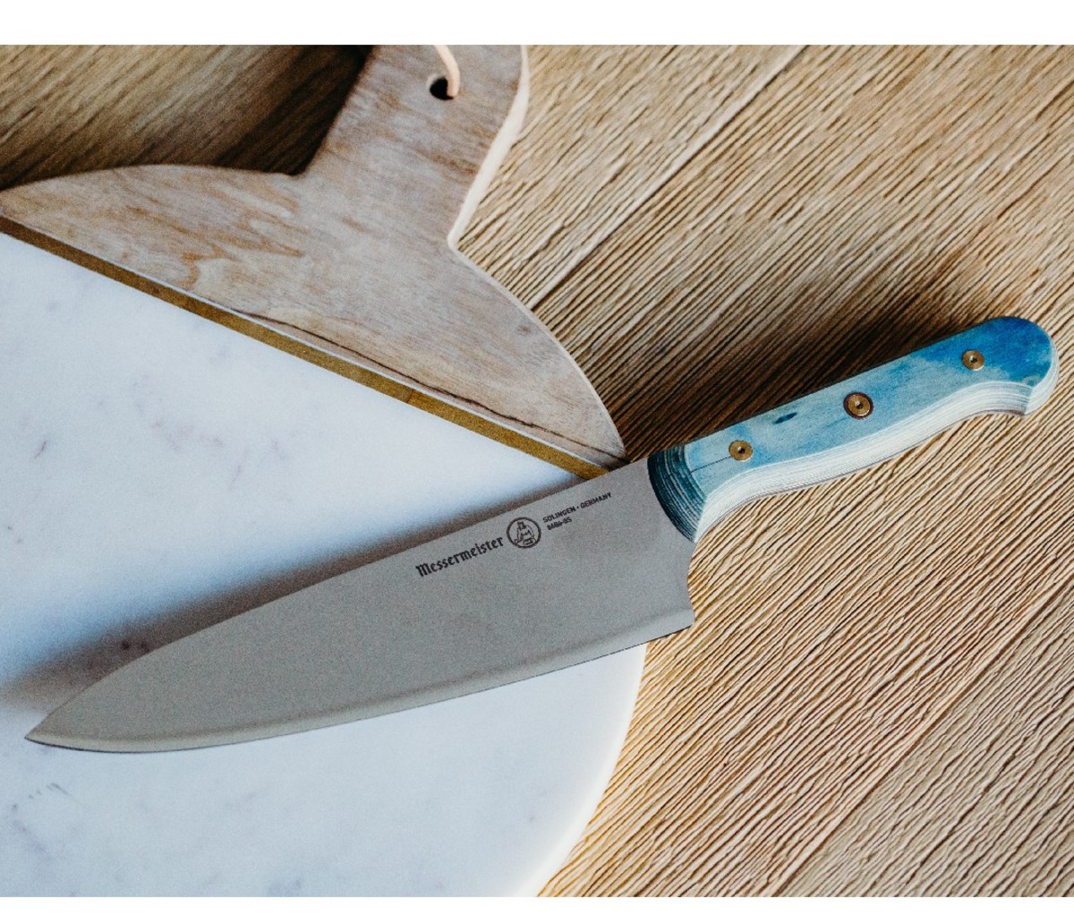Messermeister Custom Chef’s Knife on a white round cutting board on a wood counter