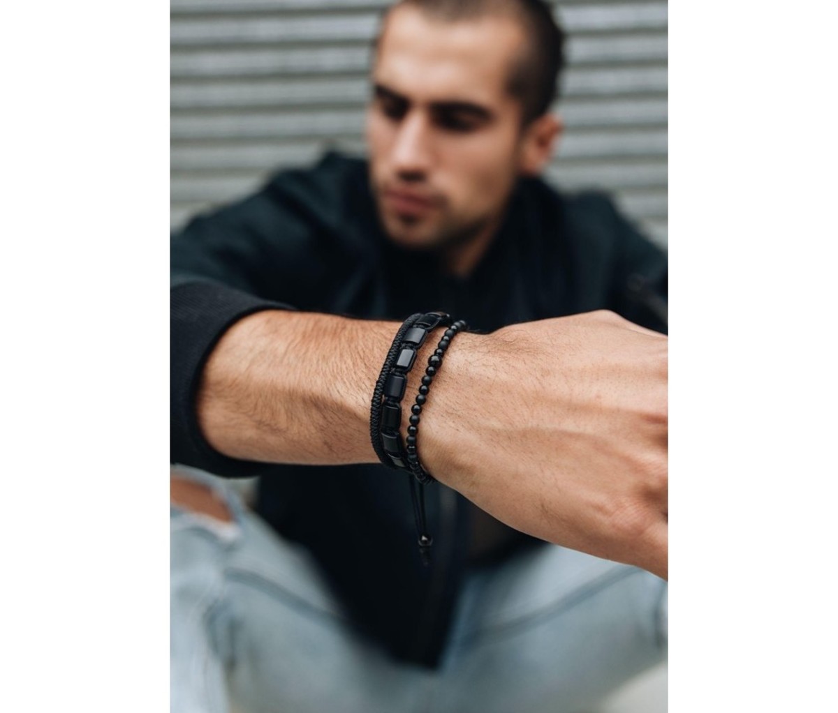 Seated man wearing three black casual MANSSION bracelets on one wrist