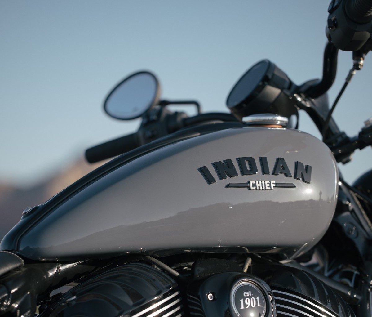 Side profile of Indian Chief Motorcycle gas tank with black lettered "Indian" logo on a gray tank