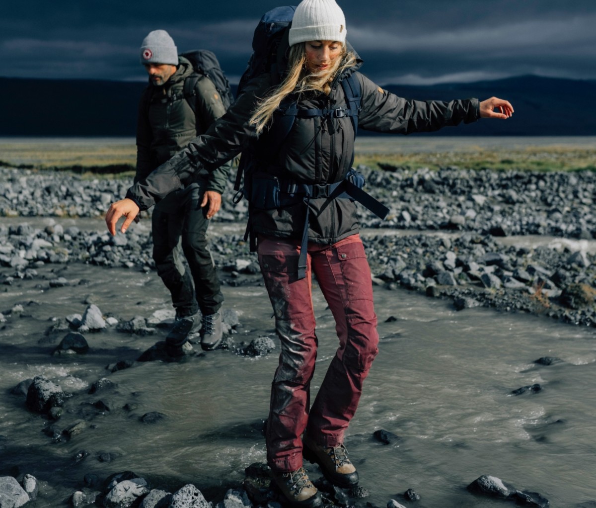 Woman wearing purple Keb trousers walking through a rocky stream