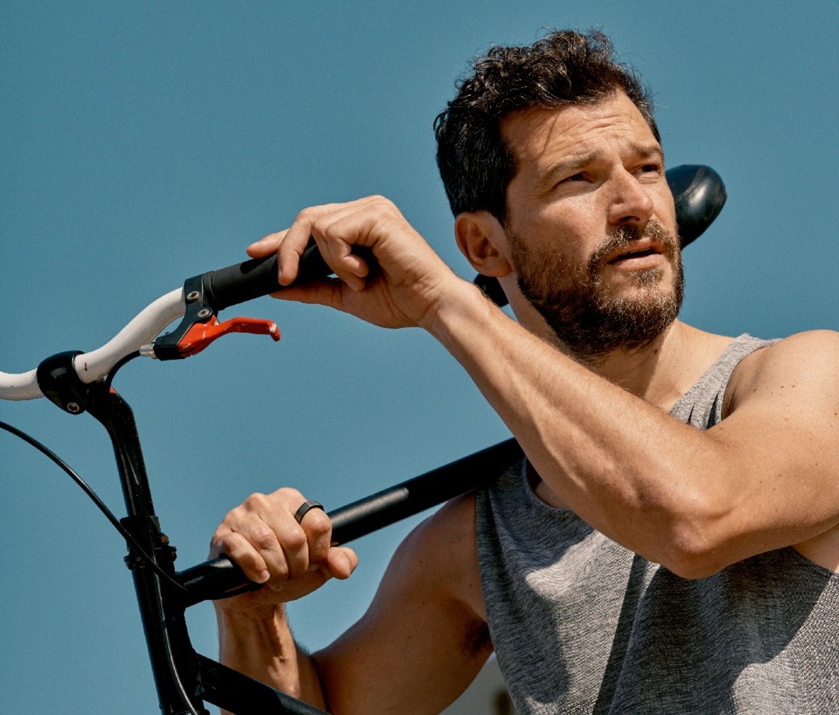 Caucasian male holding bike on shoulder looking off into distance