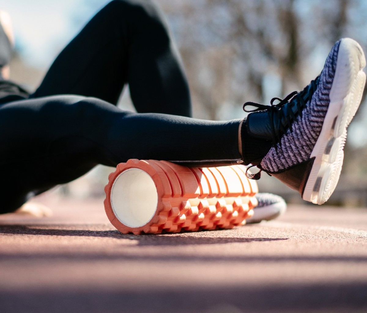 Man using an orange foam roller on calf, closeup