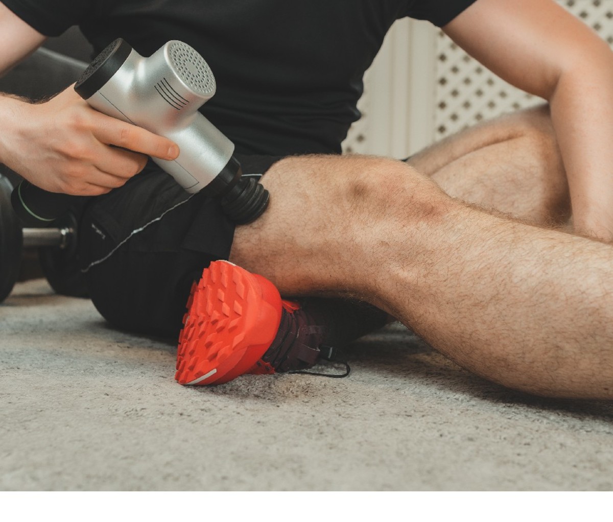 Man using a massage gun on quad muscles, closeup