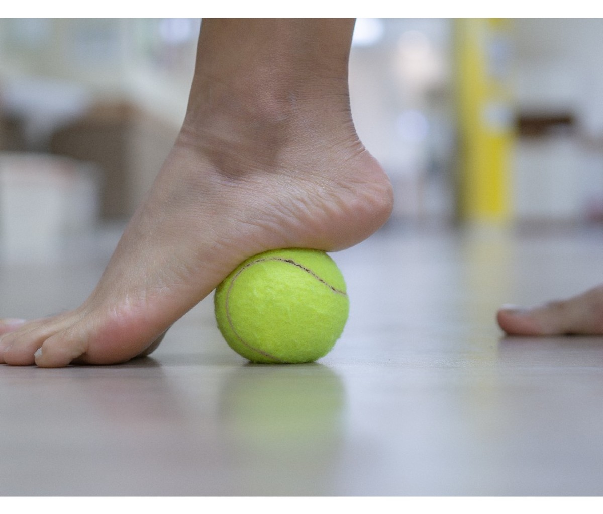 closeup of foot stretch with a tennis ball under the arch