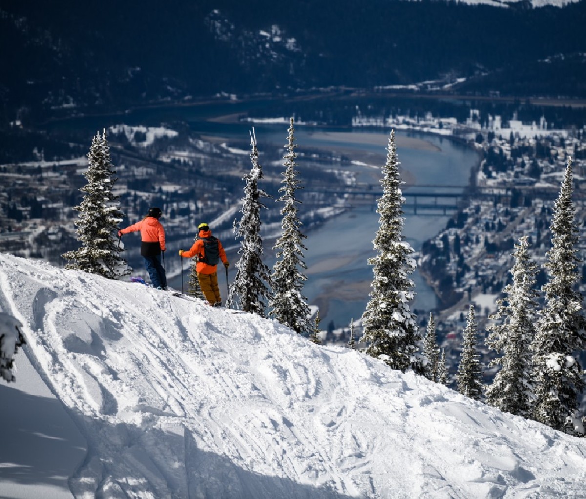 A pair of skiers look down to the town of Revelstoke and Columbia River, from Revelstoke Mountain Resort.