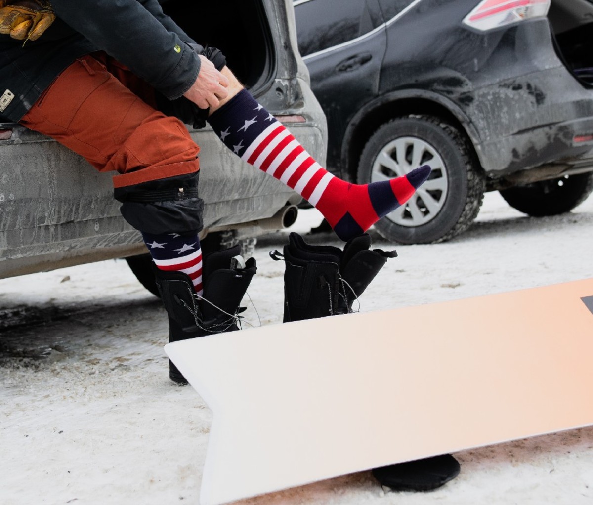 Man putting on a pair of stars & stripes designed Darn Tough Vermont Ski and Snowboard Socks