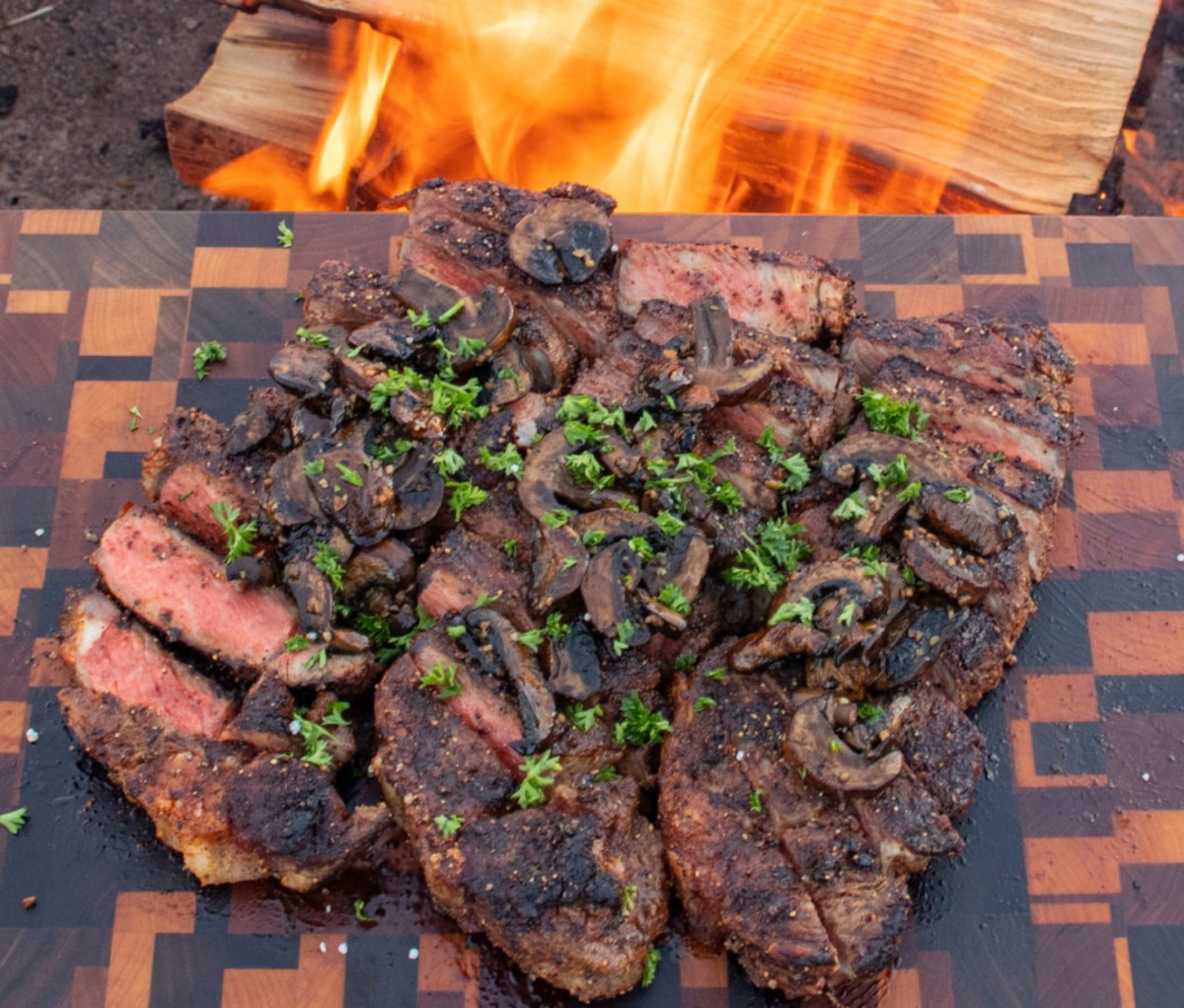 New York Strip Steaks cut up on a wooden cutting board campfire cooking