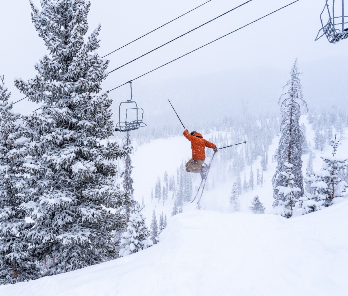 Skier taking a jump near a chair lift at Monarch Mountain