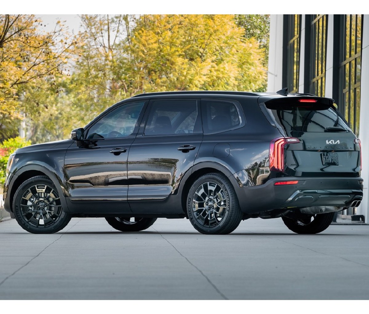Black 2022 Kia Telluride parked beside a building with trees in the background