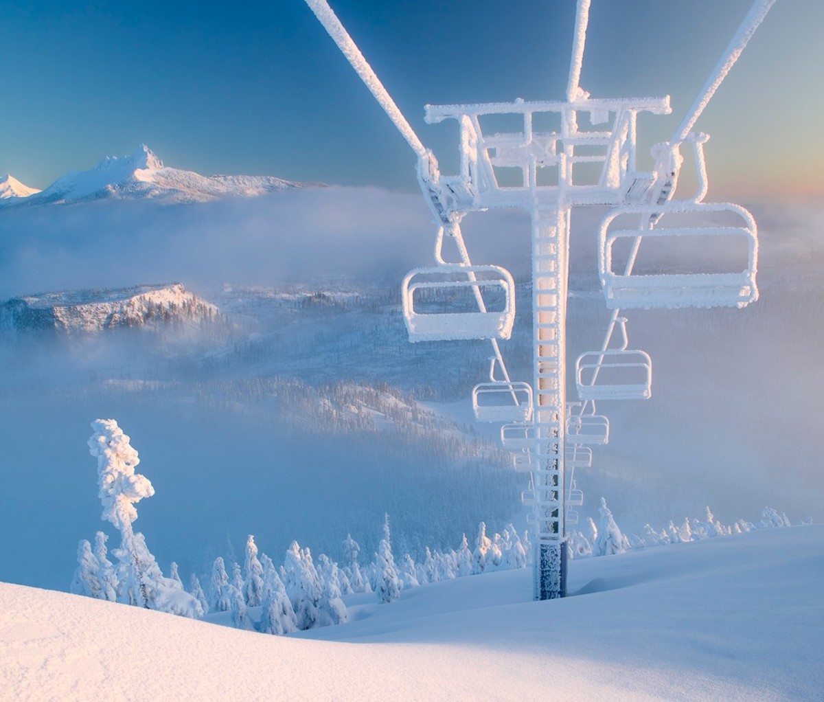 Empty snow-covered chair lift facing downhill at Hoodoo Ski Area