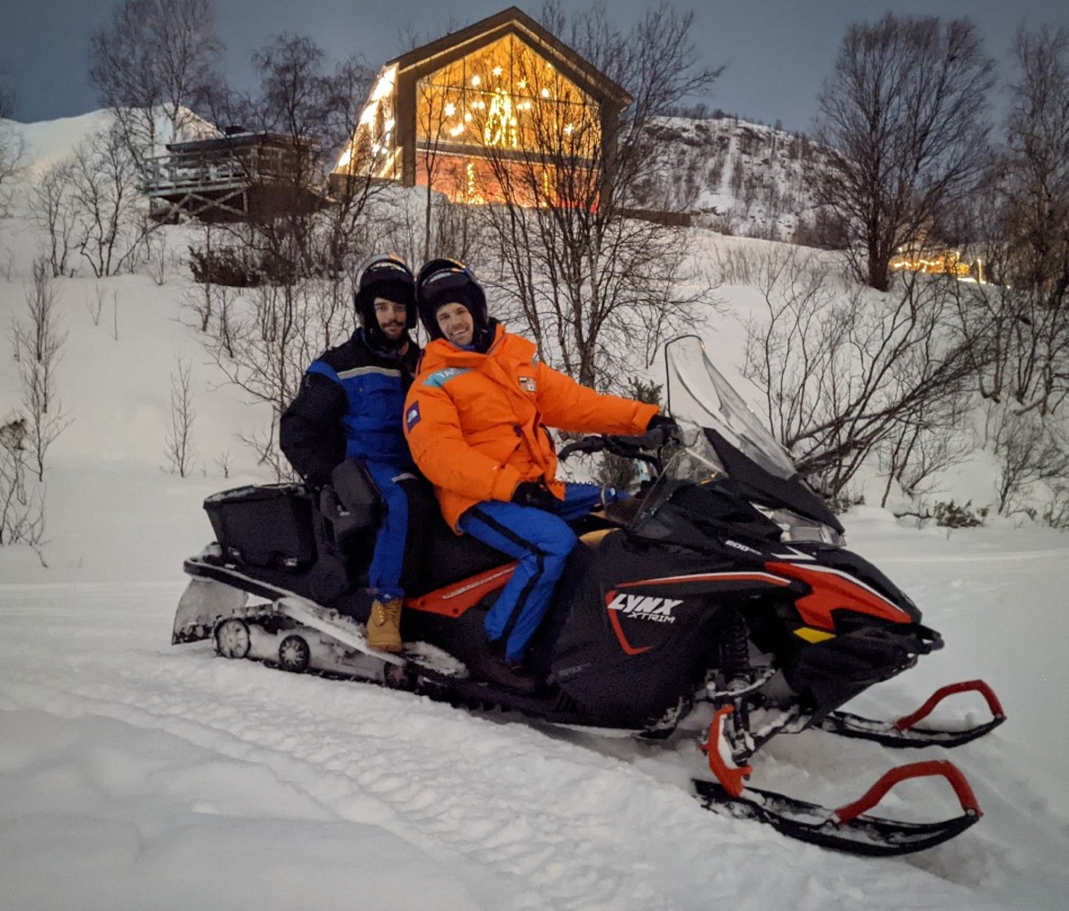 Two riders in parkas on a snowmobile in Kirkenes, Norway