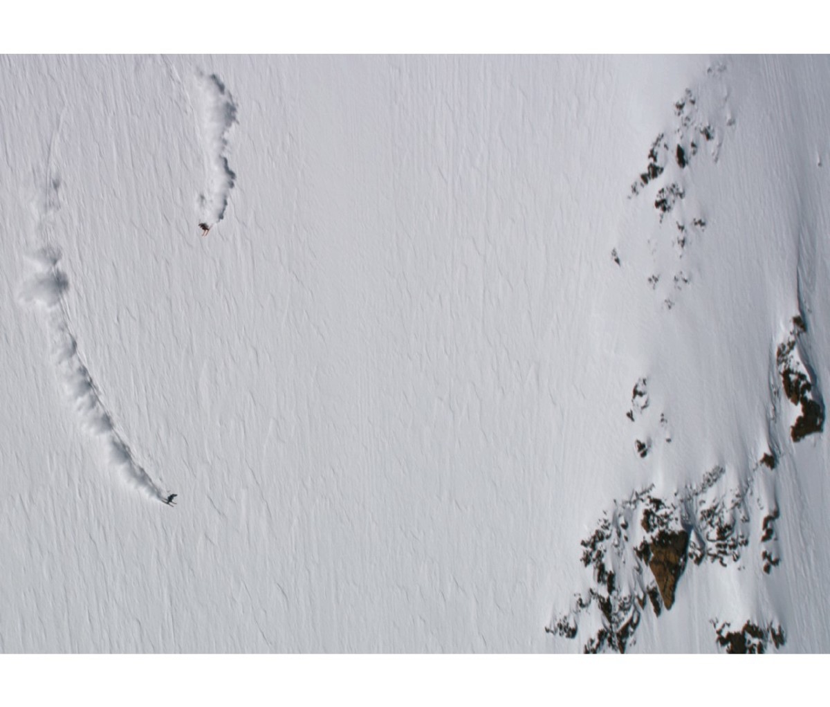 Big Mountain Skiers Sam Anthamatten and Jeremie Heitz skiing down steep powder, long aerial view