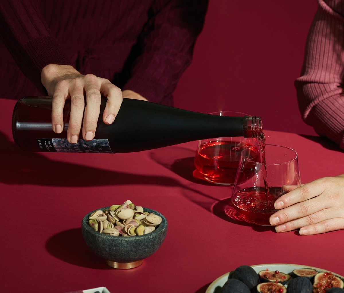 Person pouring two glasses of SomethingElse Kally chardonnay-based fruit beverage