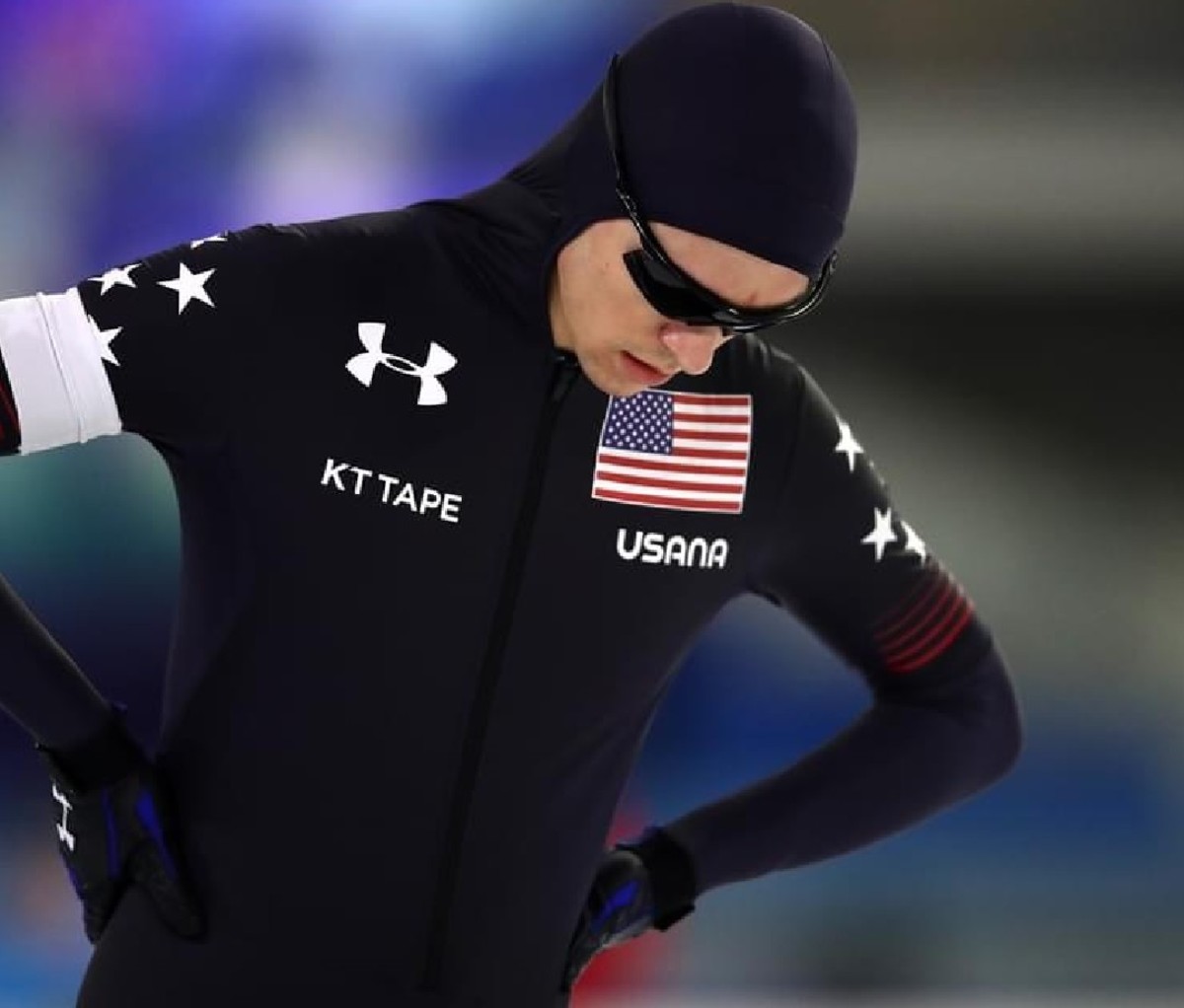 Team USA speed skater Conor McDermott-Mostowy in speed skating bodysuit on the ice with hands on hips