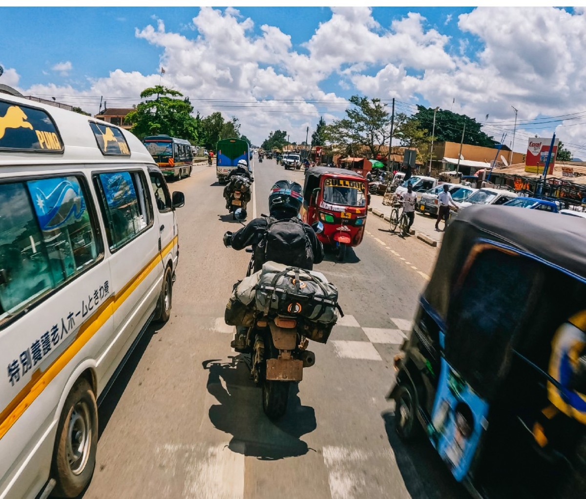 Motorcyclist splits lanes through traffic in an African city