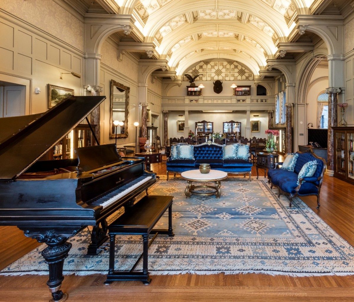 Opulent room with piano, blue velvet sofas, and blue rug
