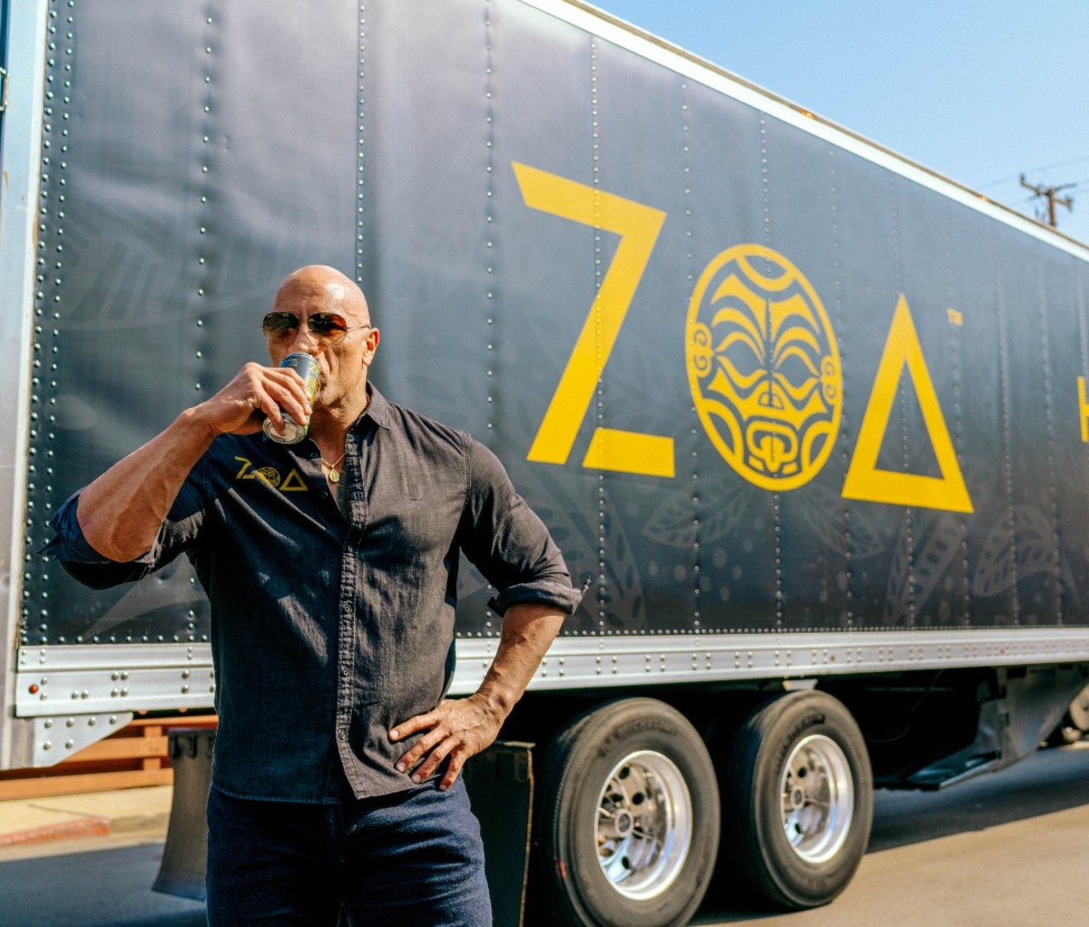 Dwayne Johnson drinking Zoa energy drink in front of branded truck