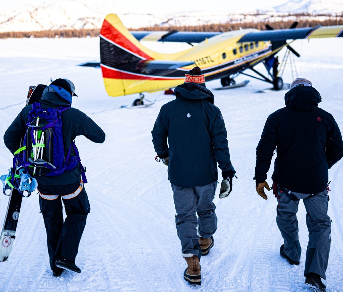 Heli ski guides and clients walk to small yellow airplane