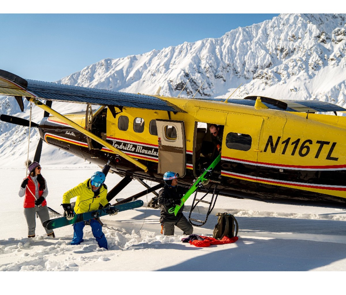 Heli-ski clients and guides unload small twin-engine plane at the top of the mountain in Alaska