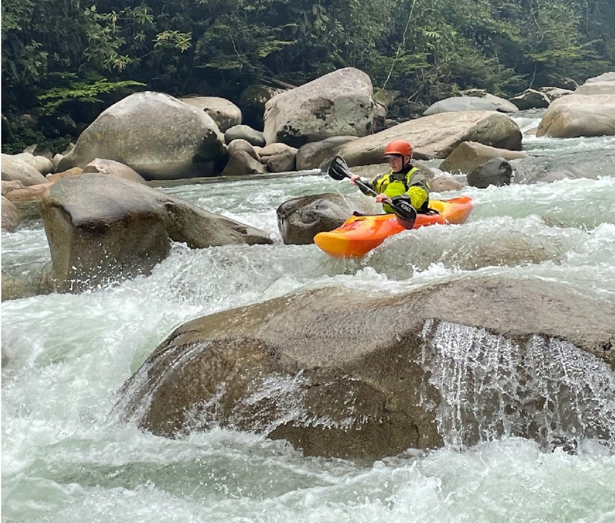 Solo kayaker heads down a small whitewater shelf on an river in Ecuador
