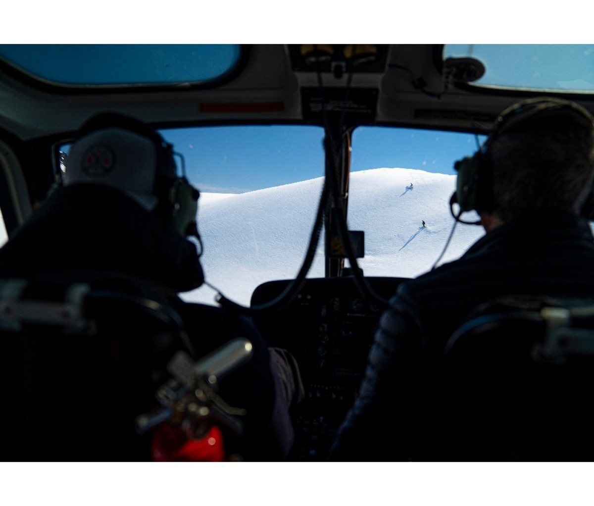 Interior of helicopter. Pilots watching skiers through the cockpit