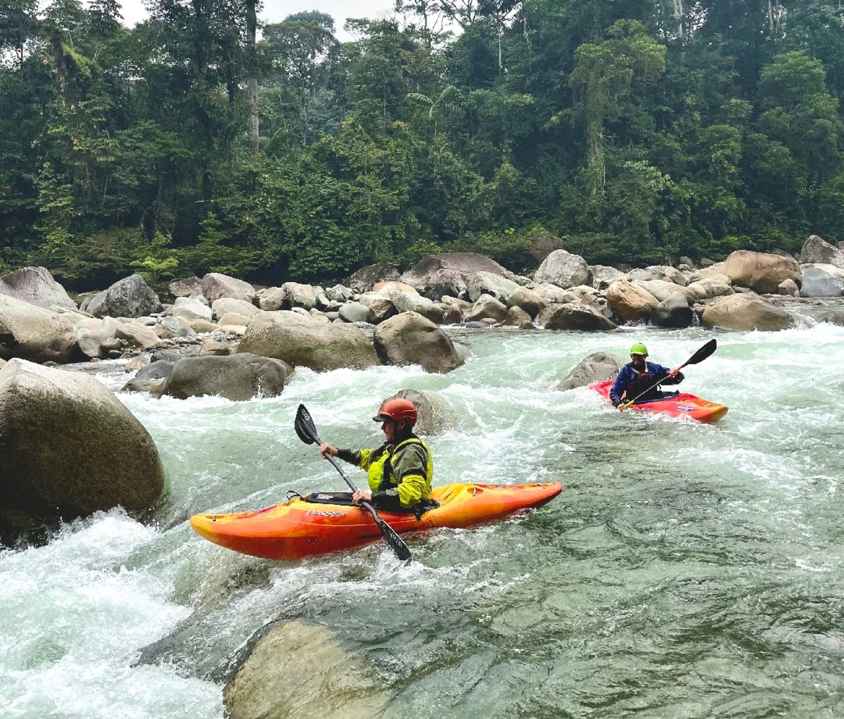 Two solo kayakers head down a drop of whitewater on a river in Ecuador