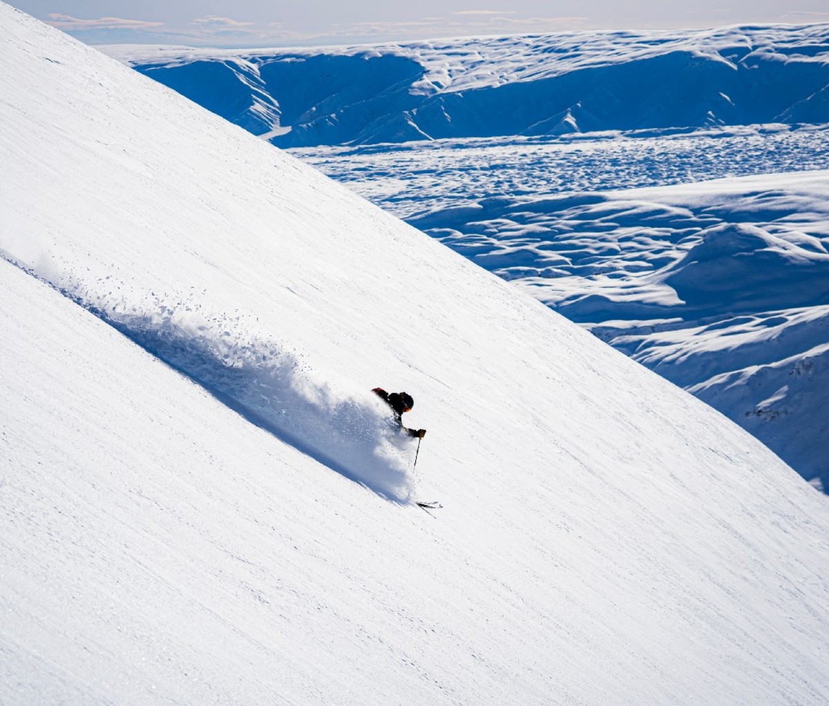 Heli-skier skiing down a powdery slope in Alaska