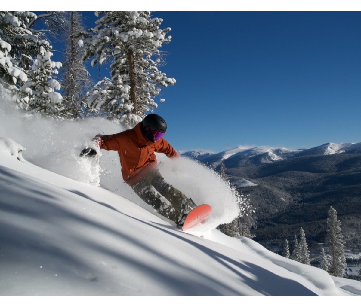 Snowboarder sprays powder during a turn on a run at Winter Park Resort.