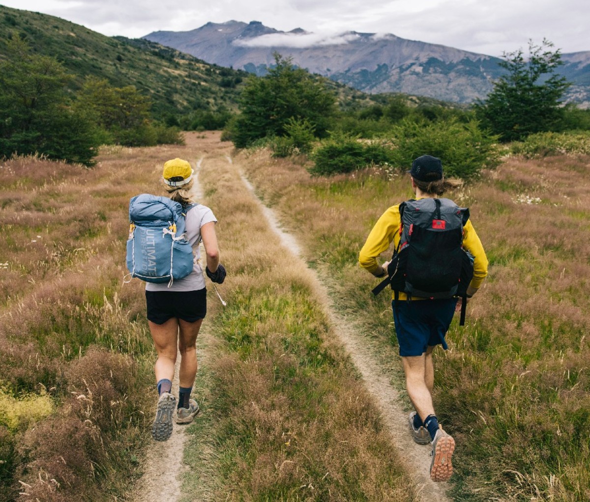 Two fastpackers trek along a grassy dirt trail in the flats of Torres del Paine National Park