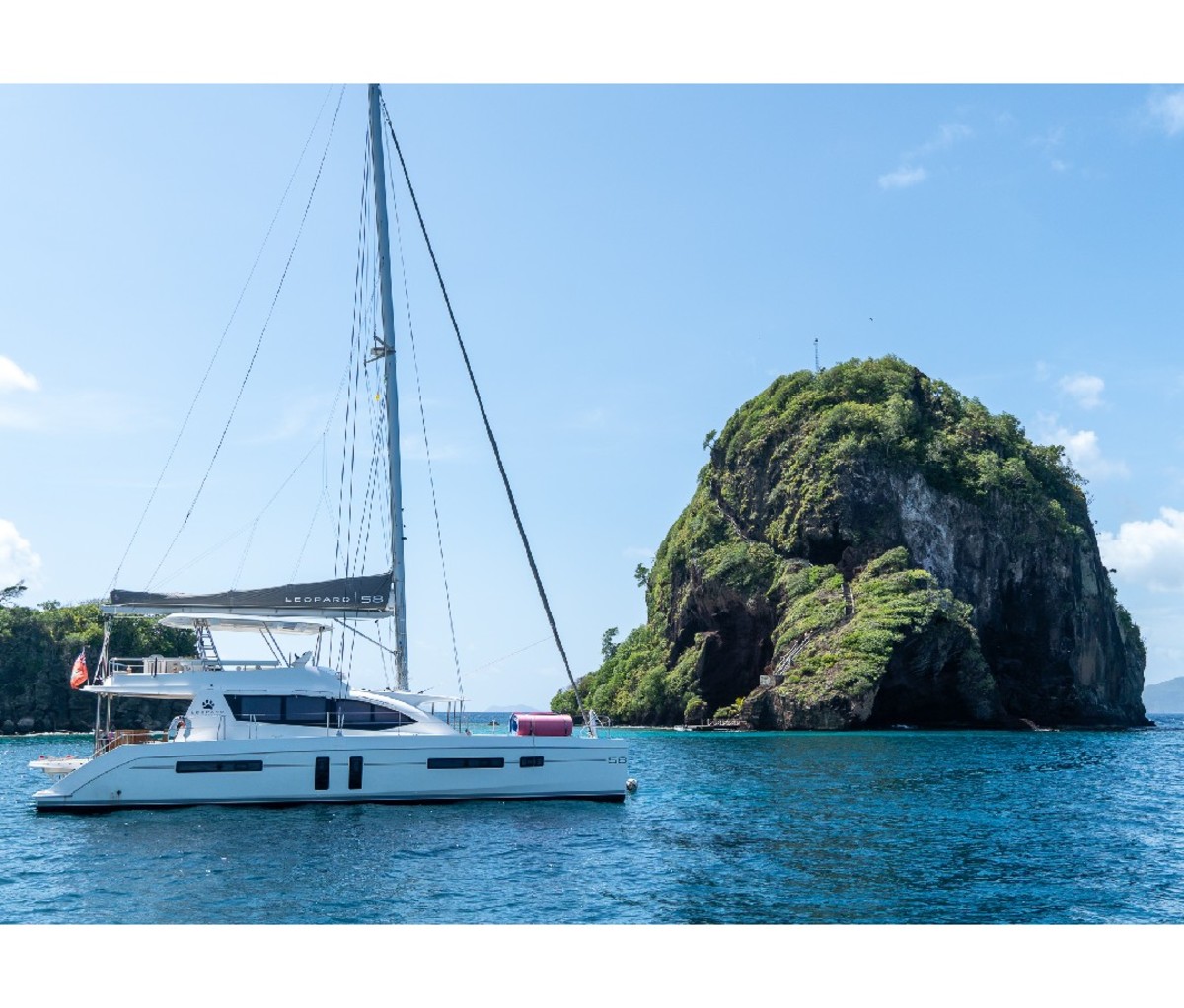 Sailing yacht parked by a tropical outcrop.