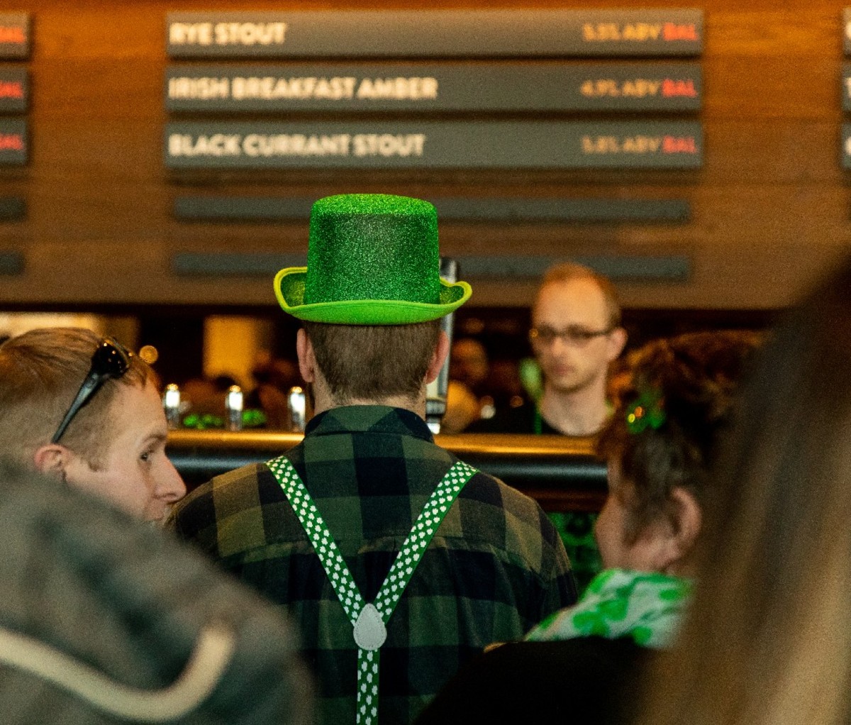 Man in green top hat standing at the bar at Guinness Open Gate Brewery in Halethrope, MD