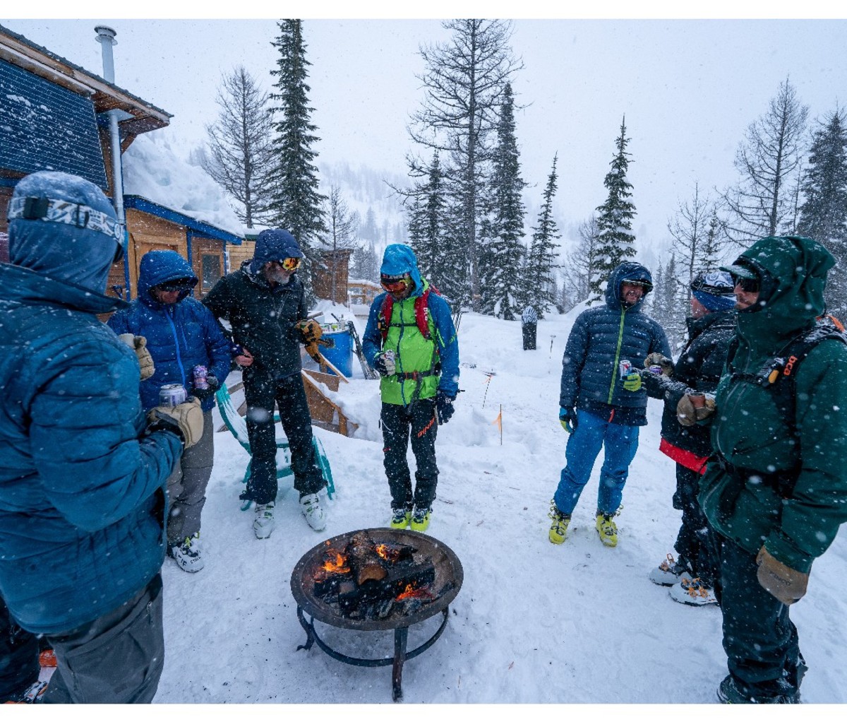 Group of skiers gather around a grill outside a lodge with beers for apres ski.
