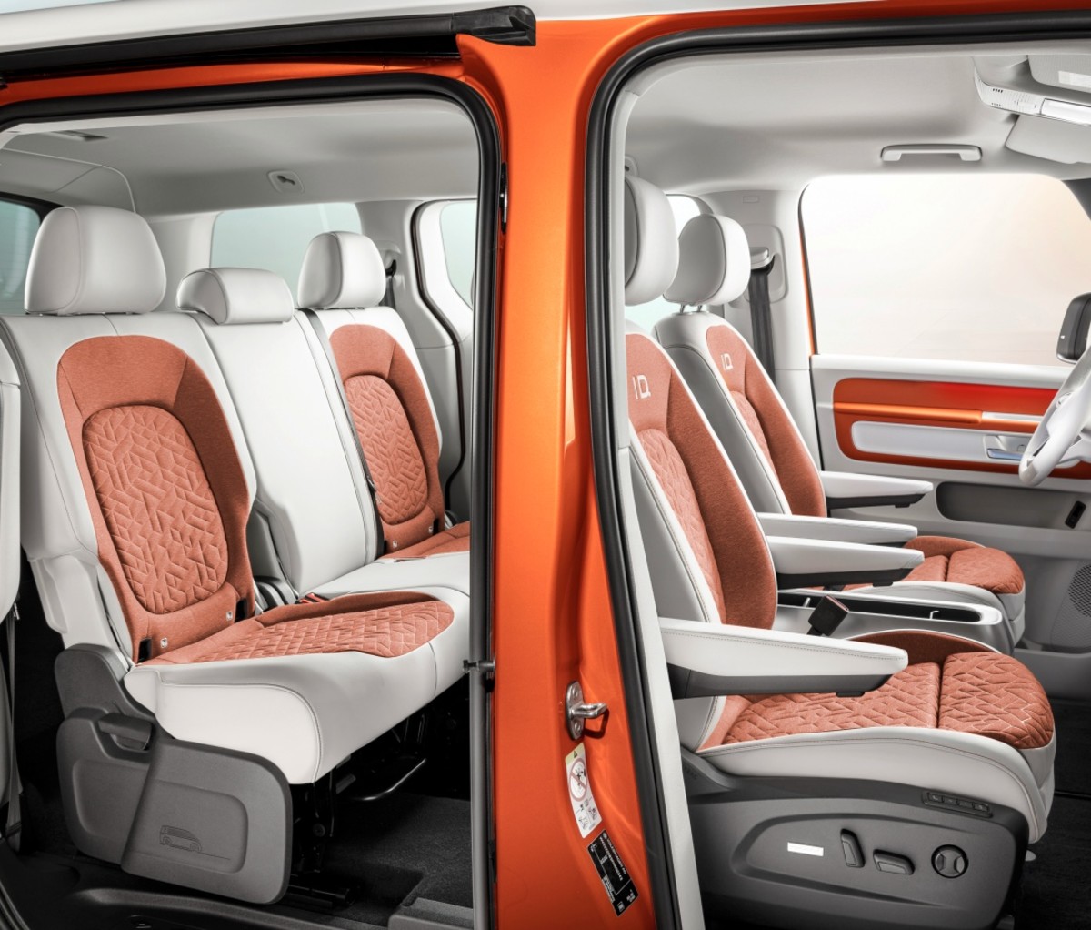 VW Id.Buzz interior showing front and rear passenger seats in orange and white fabric