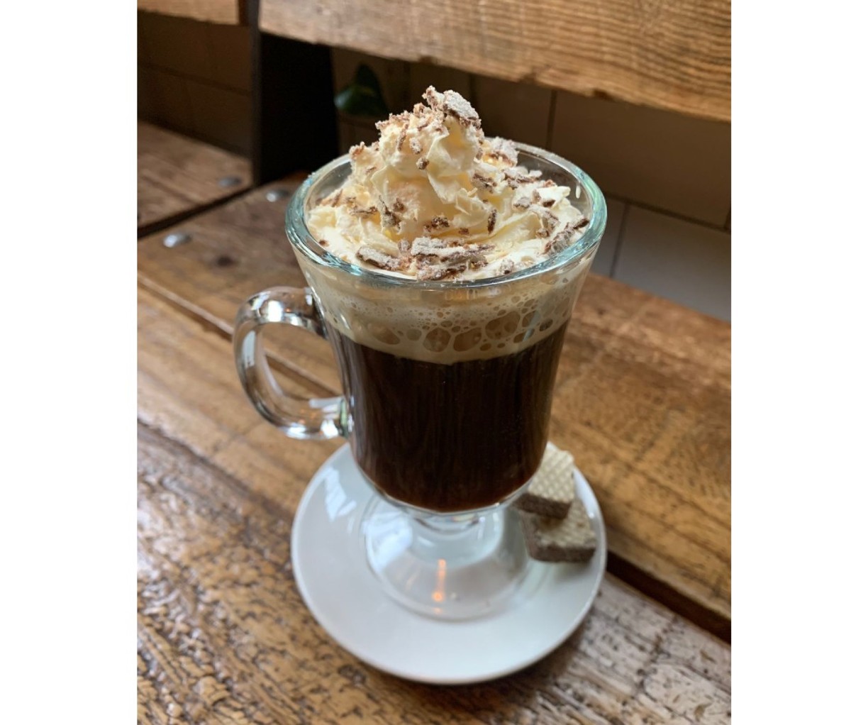 Clear glass of coffee with cream on top