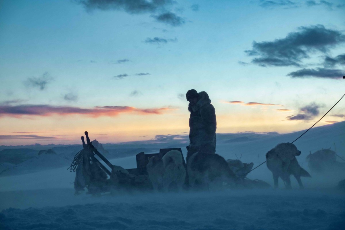 Nikolaj Coster-Waldau kneels on his sled at dusk during a scene from Netflix's "Against the Ice"