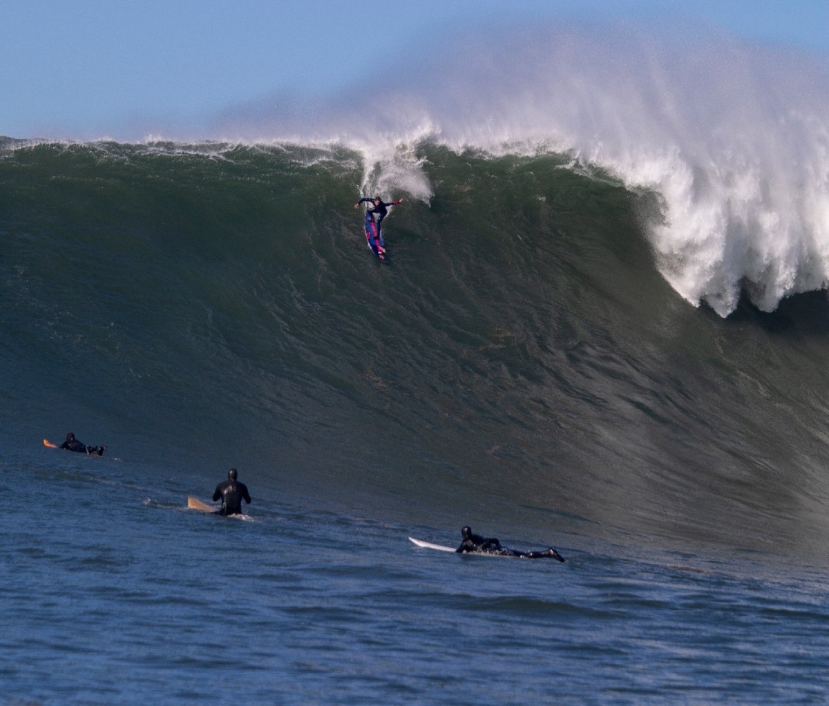 Kai Lenny rides down the crest of a giant wave.