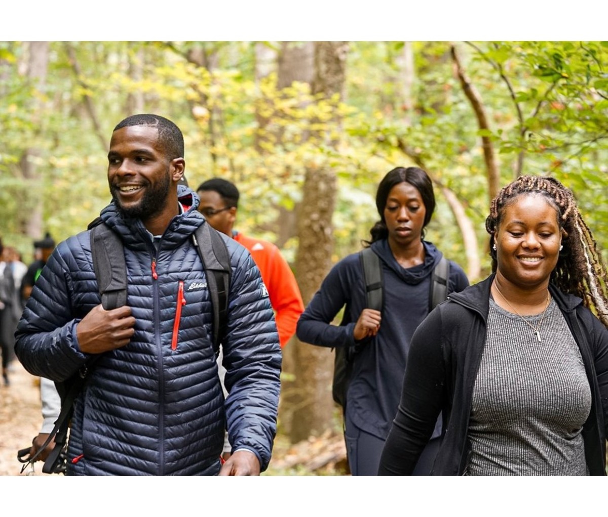 Group of Black men and women hiking through forested area