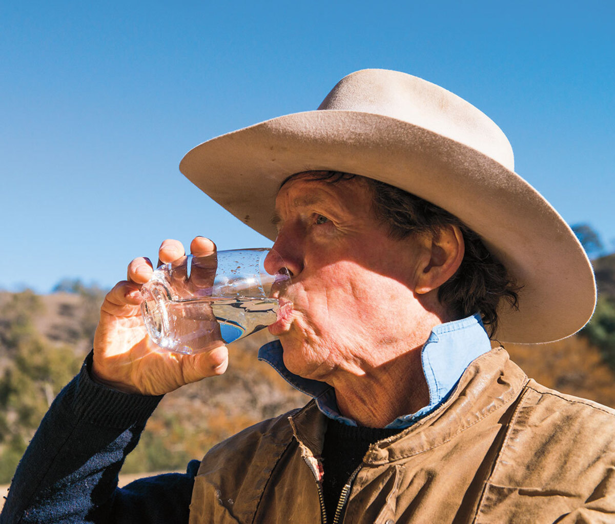 Man in cowboy hat drinking water