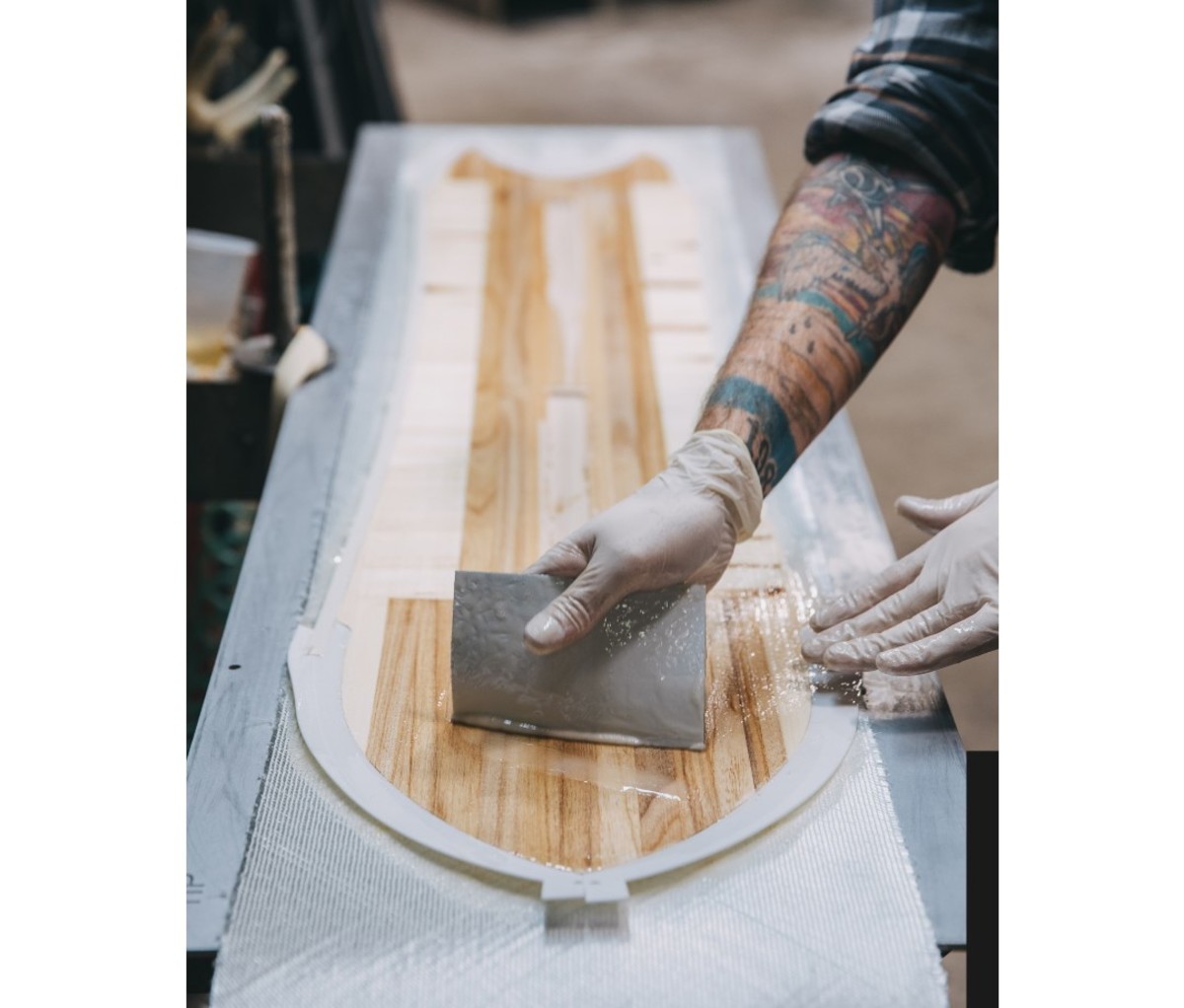 Man with tattooed arm making snowboard