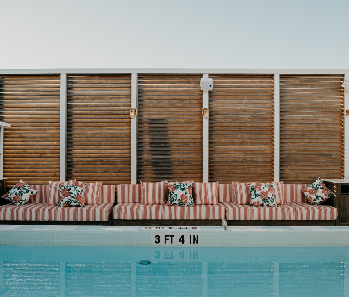 Rooftop pool with pink and white striped lounge chairs and wood-plank wall