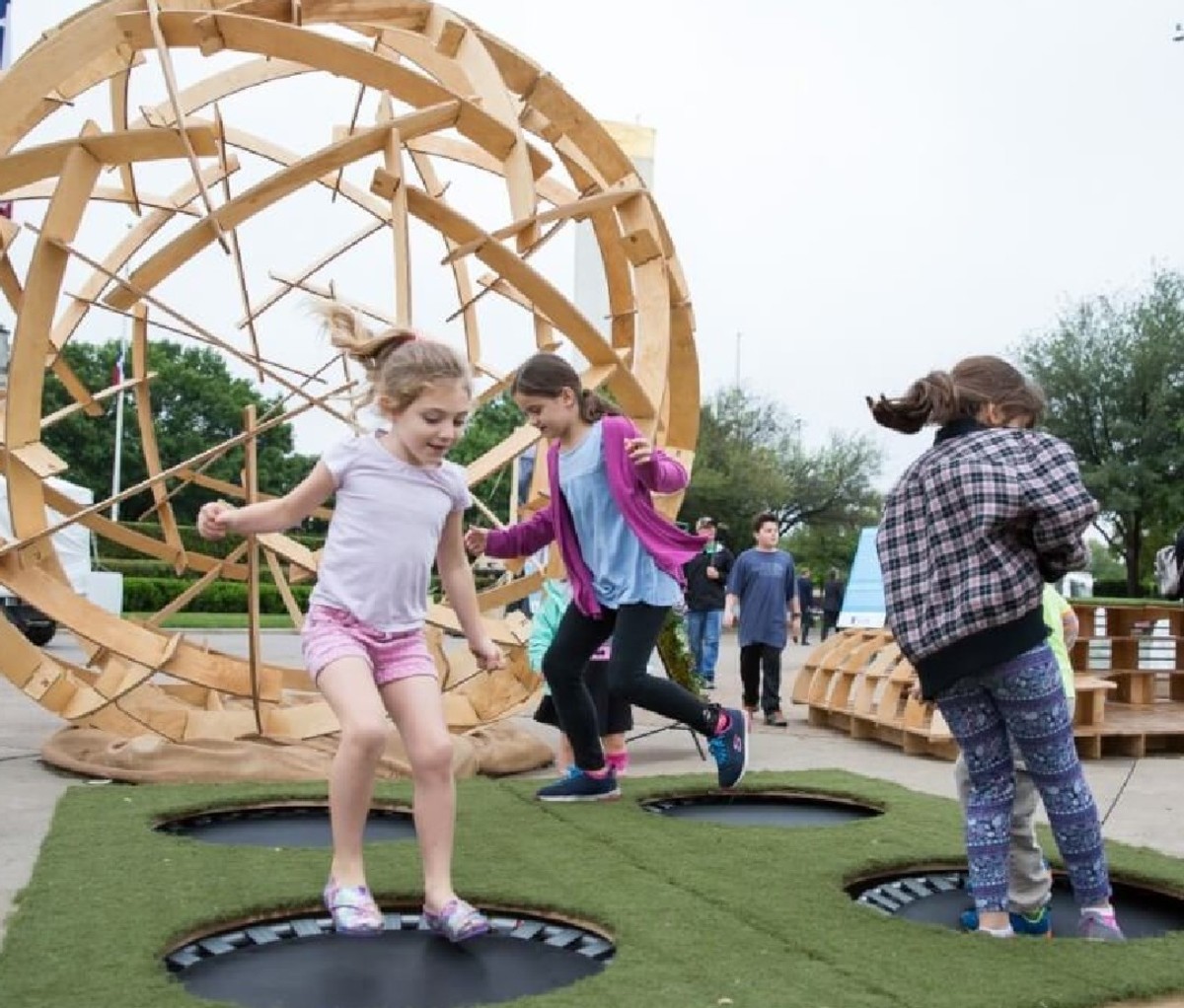 Children playing outside by a large wooden globe at EarthX in Dallas, TX