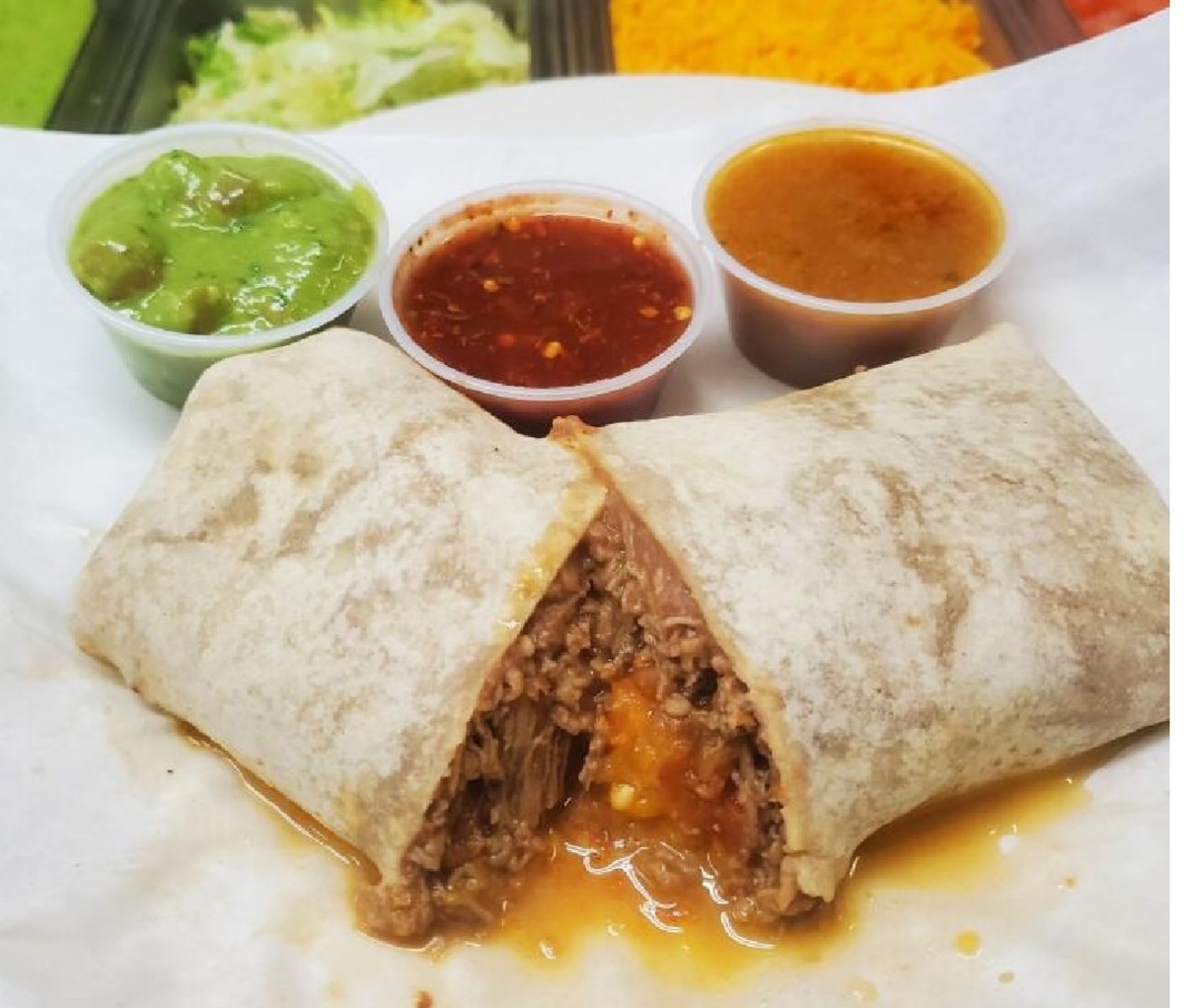 Burrito cut in half with three salsas on a plate from Al & Bea’s Mexican Food