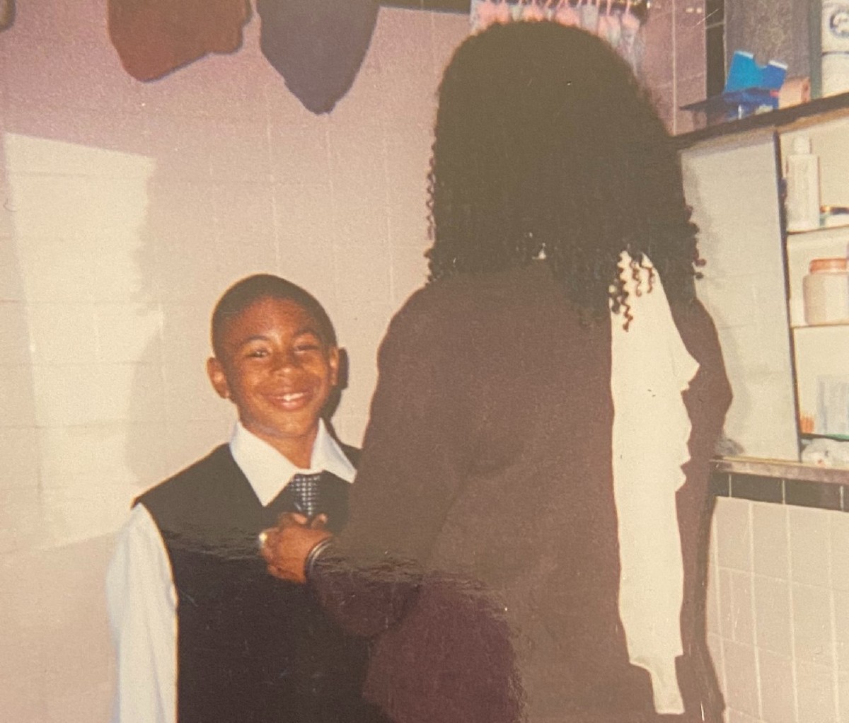 Blaise Ffrench as an adolescent in a suit, with his mom fixing his tie.