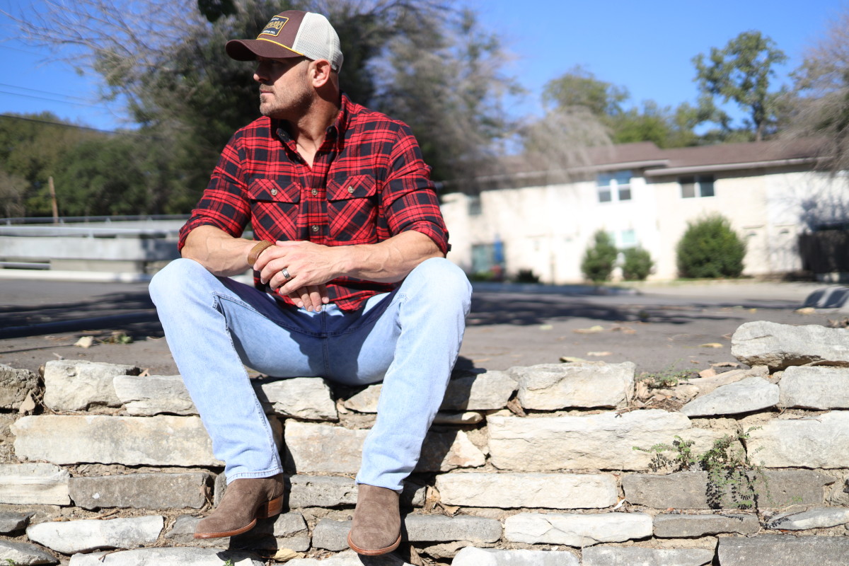 Mike Sarraille sitting outside on a stone fence in Austin.