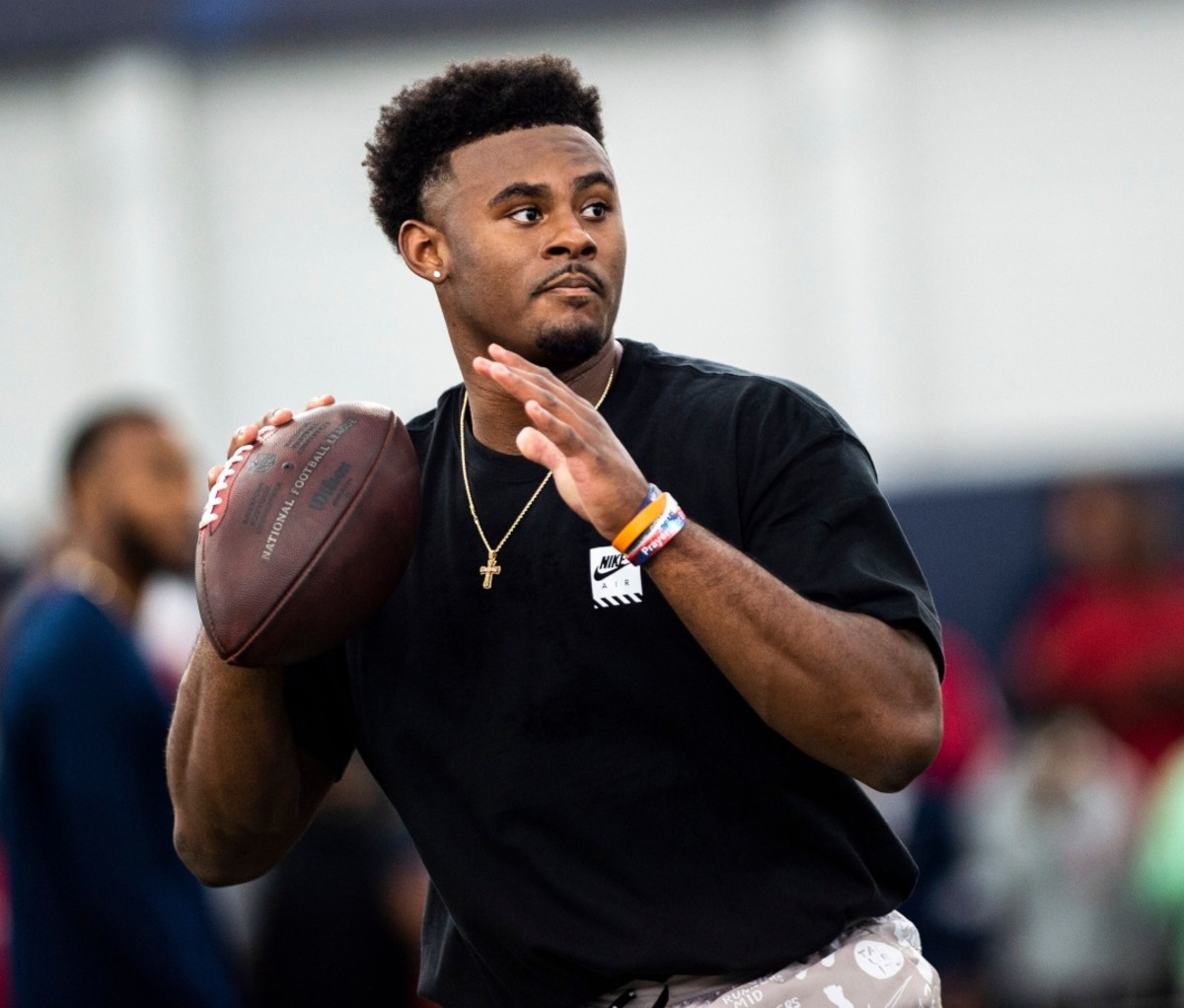 Malik Willis, wearing a black shirt and a gold necklace, gets ready to throw a football. NFL Draft 2022